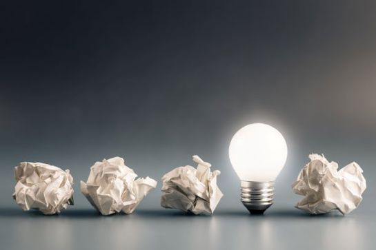 Lightbulb And Crumpled Balls Of Paper