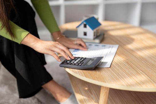 Woman With Calculator, Spreadsheet And Model House