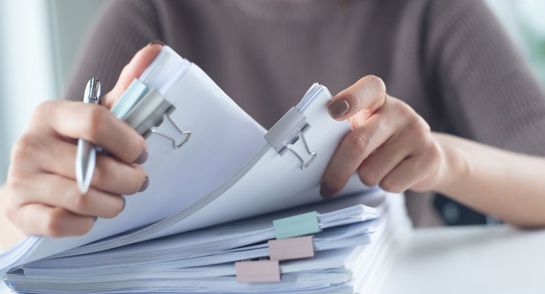 Person Reviewing Stacks Of Documents